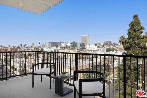 Elevated view from a balcony overlooking a cityscape with buildings and trees visible.