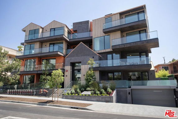 Front view of a modern multi-story building with balconies and large windows.