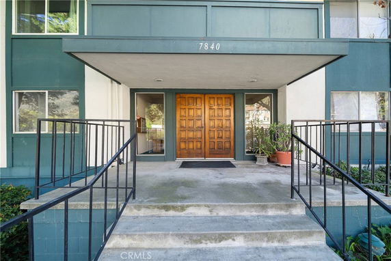 Entrance of a multi-story building with a covered porch and double doors.