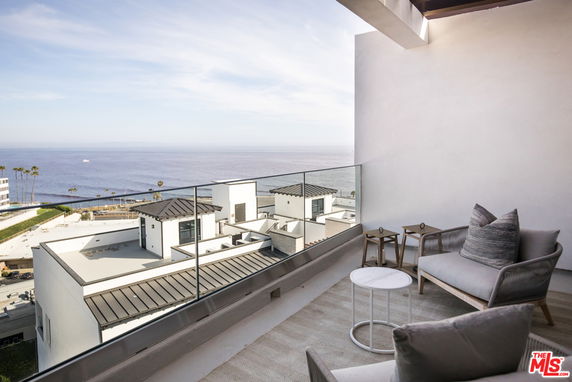 View from a rooftop patio overlooking the ocean and surrounding rooftops.