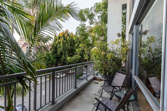 Balcony view with chairs and potted plants overlooking the street.