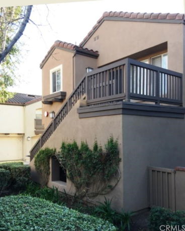 Front view of a two-story house with a staircase and balcony.