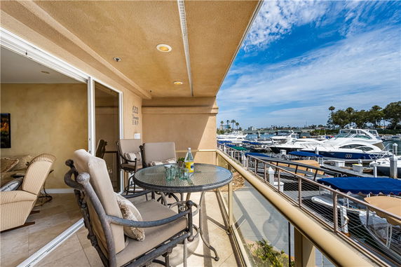 Balcony with seating overlooking a marina with yachts.