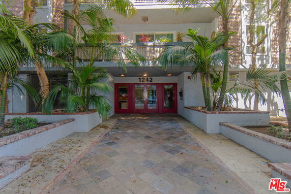 Entrance view of a building with red doors and surrounding greenery.