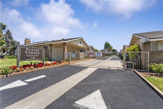 Front view of a gated community building with a sign and driveway.