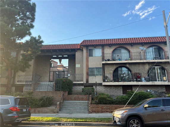 Front view of a two-story apartment building with a tiled roof and balconies.