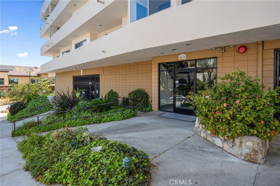 Front view of a multi-story building with a glass entrance and surrounding landscaping.