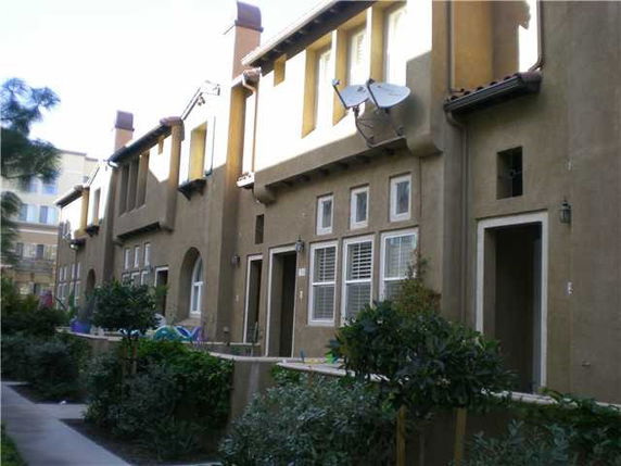 Front view of a multi-story residential building with balconies and satellite dishes.
