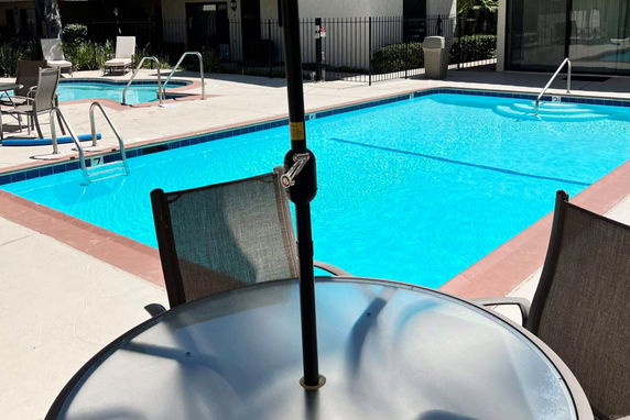 Outdoor swimming pool area with a table and chairs.
