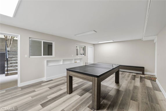 Room featuring a table with a net, likely for table tennis, with wooden flooring.