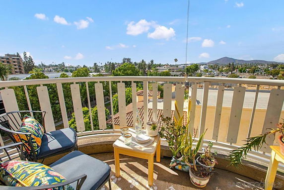 View from a balcony showing buildings, trees, and distant hills under a clear sky.