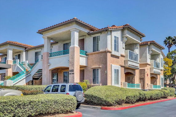 Front view of a two-story residential building with balconies and exterior stairs.