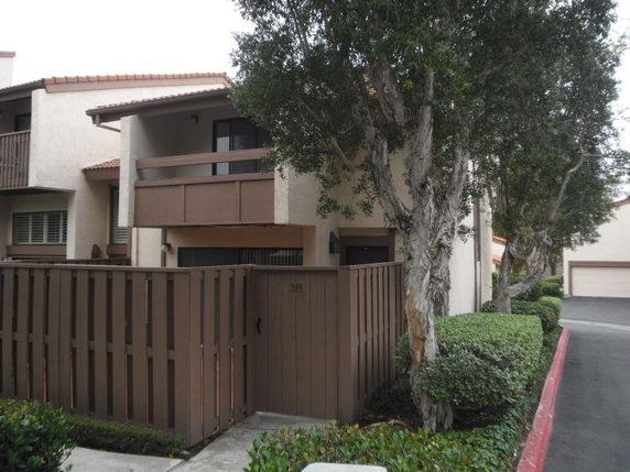 Front view of a multi-story residential building with a fenced entrance and balcony.