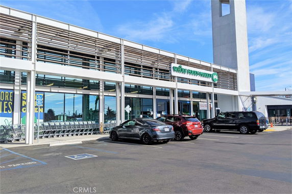 Front view of a supermarket with cars parked in the outdoor parking area.