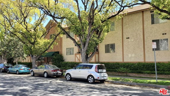 Front view of a multi-story residential building with parked cars on the street.