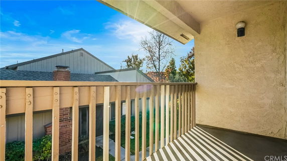 View of surrounding houses from a balcony with wooden railing.