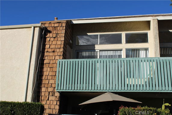 Front view of a building with large windows and a balcony with a blue railing.