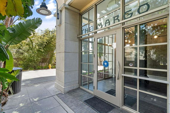 Entrance view of a building with large glass doors and a sign above.