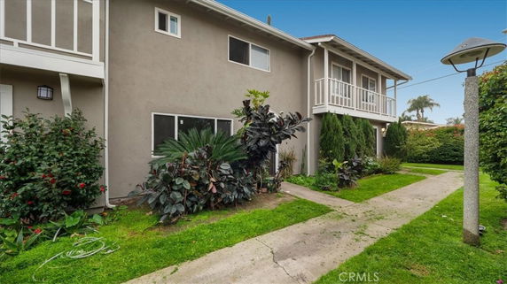 Front view of a two-story house with balconies and garden.