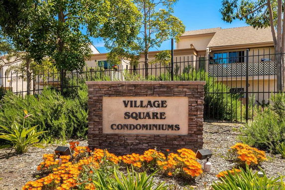Front view of a condominium complex with signage and landscaping.