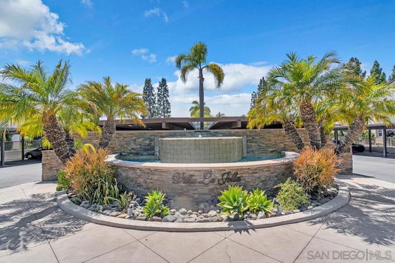 Front view of a building entrance with a stone fountain and palm trees.