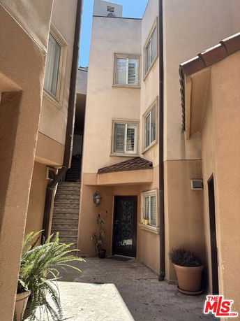 View of an exterior entrance to a multi-story building with stairs.