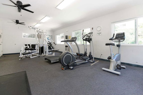 Indoor gym area with various exercise equipment including treadmills and weight machines.