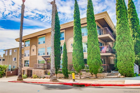 Front view of a multi-story residential building with balconies and large windows.
