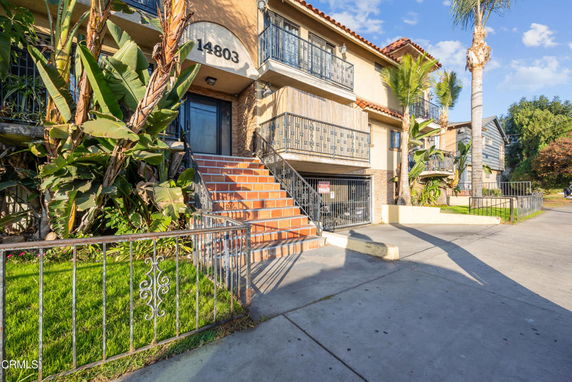 Front view of a multi-story residential building with wrought iron railings and a staircase.