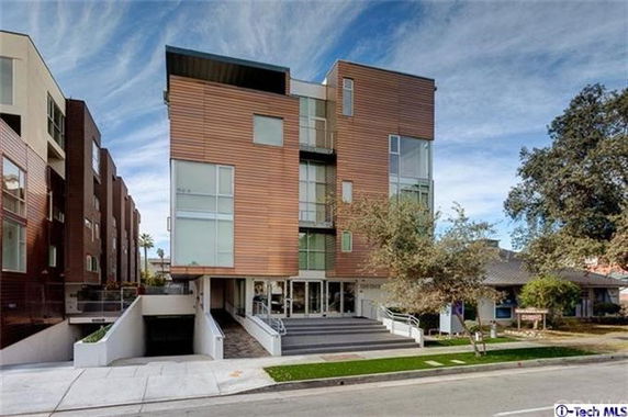 Front view of a modern multi-story building with large windows and wooden paneling.