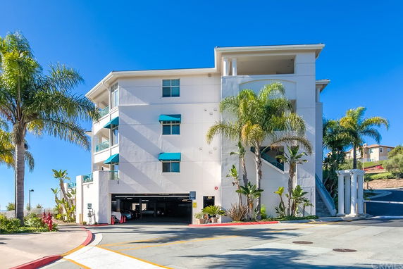 Front view of a multi-story building with blue window awnings and palm trees.