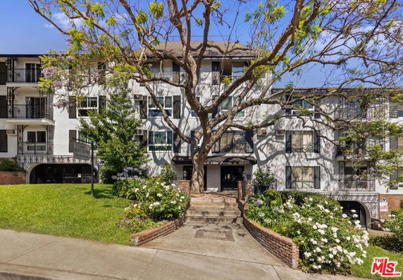 Front view of a multi-story residential building with balconies and a central entrance.