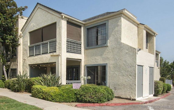 Front view of a two-story house with a stucco exterior and large windows.