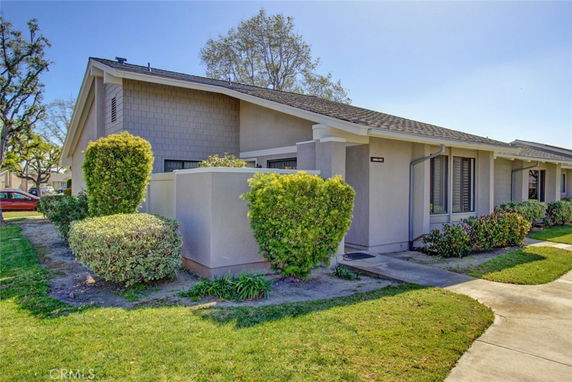 Front view of a single-story house with a sloped roof and landscaped shrubs.