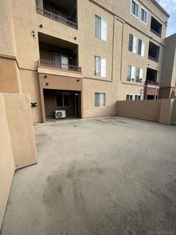 View of a multi-story building with balconies and an air conditioning unit.