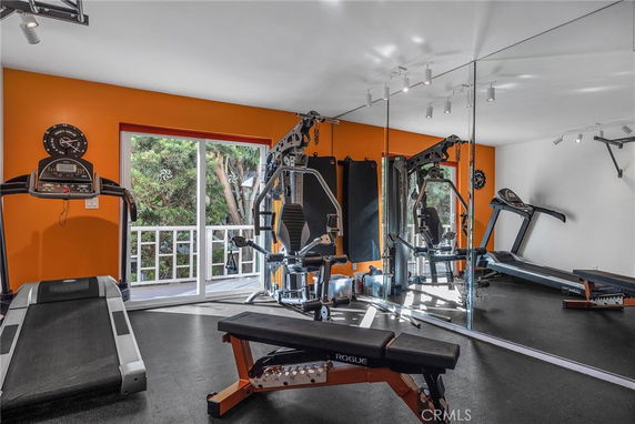 Indoor gym with exercise equipment and mirrors on the wall.
