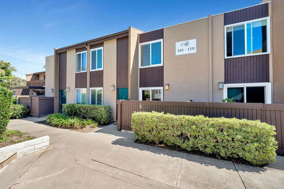 Front view of a two-story residential building with multiple units and a walkway.