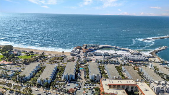 Panoramic view of a coastal area with buildings and a pier overlooking the ocean.