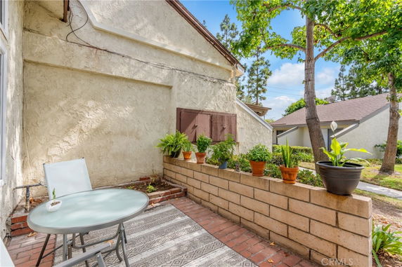 Side view of a house with a small patio area and potted plants.