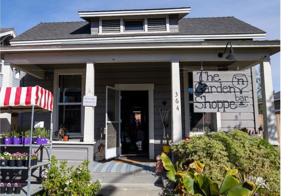 Front view of a single-story house with a porch and business signage.