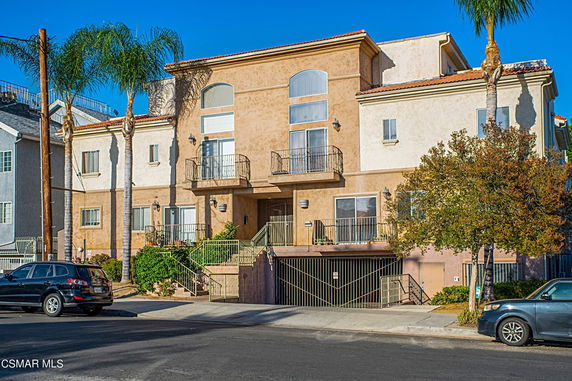 Front view of a multi-story residential building with balconies and a gated entrance.