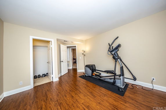 Room with exercise equipment and hardwood flooring.