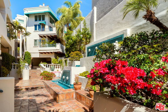 Front view of a multi-story building with balconies and a water feature.