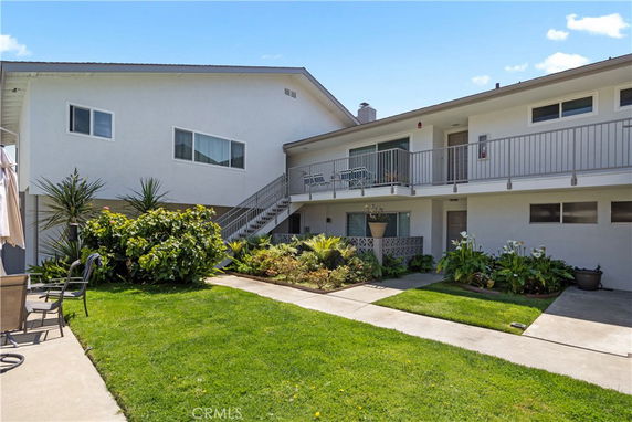 Front view of a two-story residential building with external stairs and balcony.