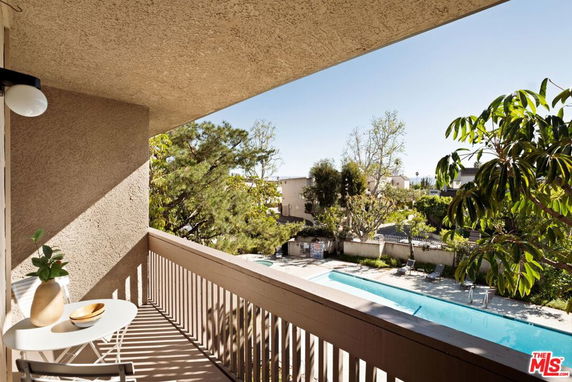 View of surrounding areas seen from a balcony overlooking a swimming pool.