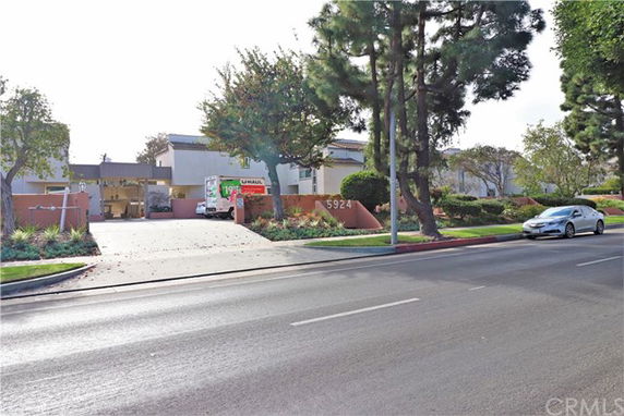 Front view of a building with a driveway and surrounding landscaping.