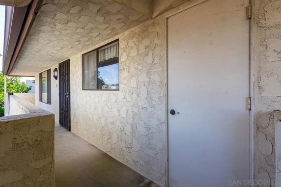 Exterior view of a building corridor with textured walls and windows.