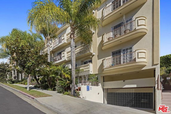 Front view of a multi-story residential building with balconies and a garage.