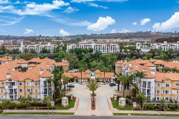 Aerial view of multiple residential buildings with terracotta roofs and surrounding green areas.