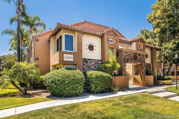 Front view of a two-story house with a clay tile roof and stone accents.